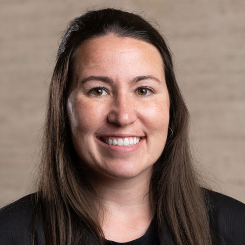 A woman with long dark hair in a dark suit.