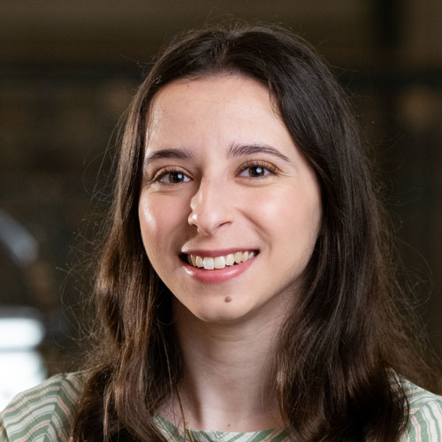 Woman with long brown hair wearing a green and white striped blouse.