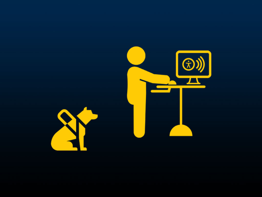 An employee at a standing desk with a screen reader with their service dog sitting behind them.