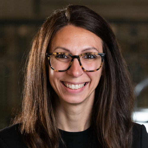 Woman with long dark hair in a black suit jacket.